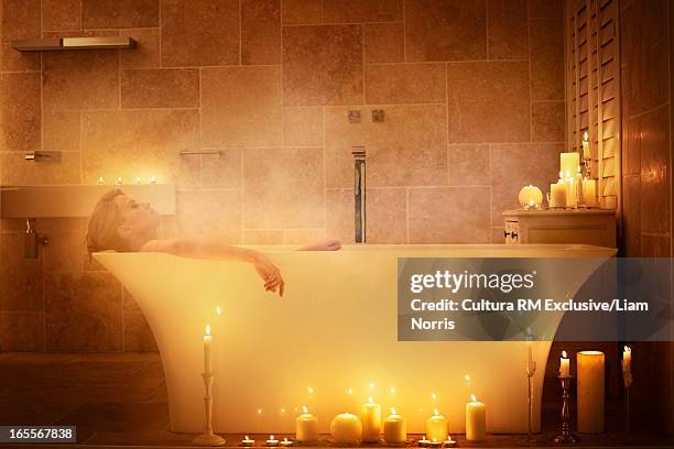 woman soaking in bathtub with candles - candle light foto e immagini stock
