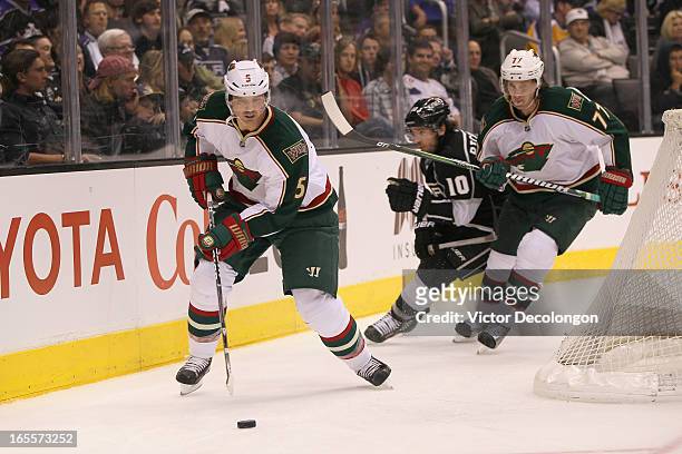 Brett Clark of the Minnesota Wild plays the puck around the net as teammate Tom Gilbert holds off Mike Richards of the Los Angeles Kings during the...