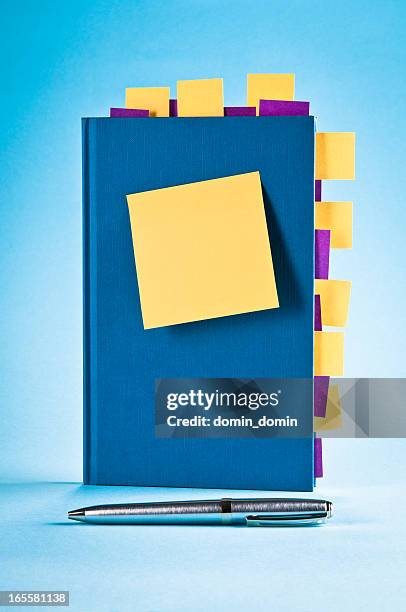 blue notepad with yellow, purple sticky post-it notes, ballpoint pen - handbook stock pictures, royalty-free photos & images