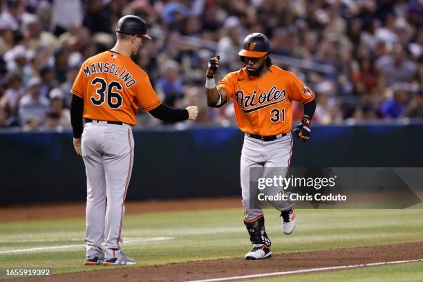 Cedric Mullins of the Baltimore Orioles high-fives third base coach Tony Mansolino after hitting a three-run home run during the fourth inning...