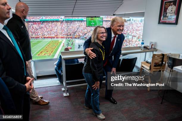 Ames, Iowa Former President Donald Trump greets and poses for photos with supporters in a private box during a NCAA college football game between...