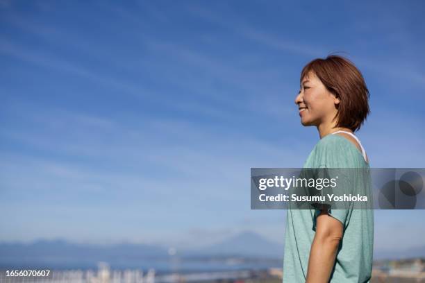 a woman enjoys yoga in a park facing the beach in the morning. - レギンス　 ストックフォトと画像