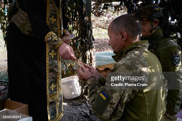 Ukrainian military chaplain Ivan gives religious images to an infantry soldier of the "Black Zaporozhian Cossacks" 72th Brigade on the frontline near...