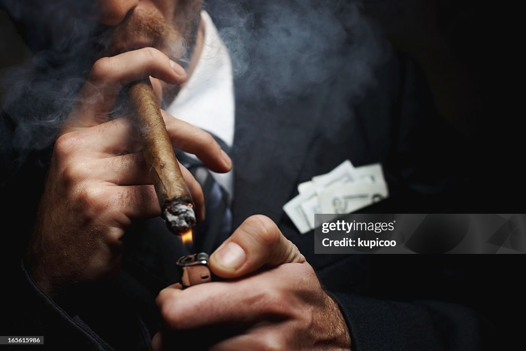 Close-up of man's hand with cigar and lighter