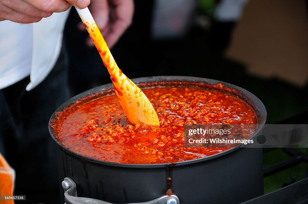 Cook Stirring a Simmering Pot of Spicy Chili