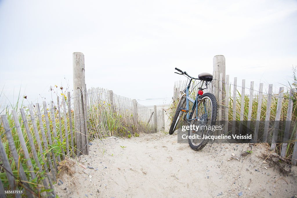 Bicycle leaning on beach fence