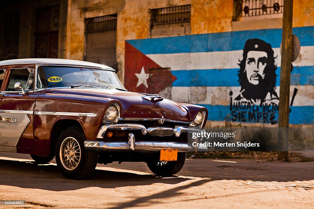 Plymouth classic car passing Cuban flag