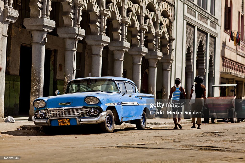 Women passing blue oldtimer car