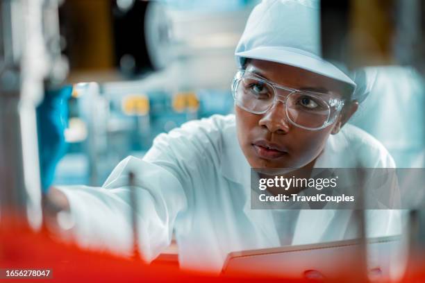 female engineer in a drinking water factory in professional uniform using digital tablet working in beverage industrial. female factory worker use digital tablet testing program in production line. - calidad fotografías e imágenes de stock