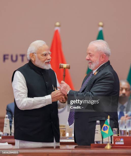 India's Prime Minister Narendra Modi hands over the gavel to Brazil's President Luiz Inacio Lula da Silva during the third working session of the G20...