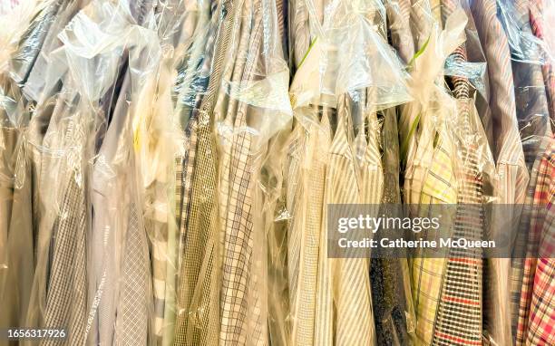 rack of freshly laundered shirts at dry cleaners - dry cleaning photos et images de collection