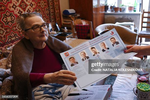 An elderly woman holds a list of candidates as she votes at home during local elections in Moscow on September 10, 2023.