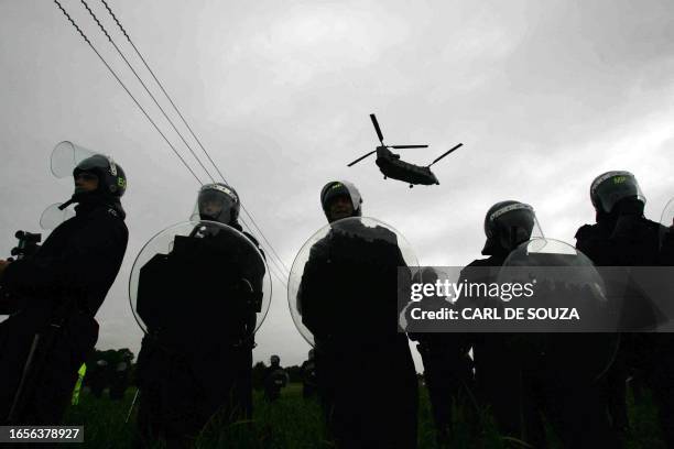 Chinook helicopter flies above riot police officers outside the perimeter fences of Gleneagles hotel where the G8 summit is taking place after G8...