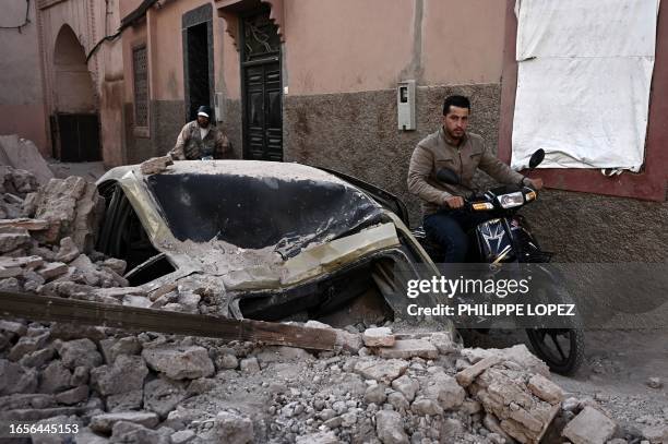 Man rides a motorcycle past rubble in the old quarters of Marrakesh on September 10 two days after a devastating 6.8-magnitude earthquake struck the...