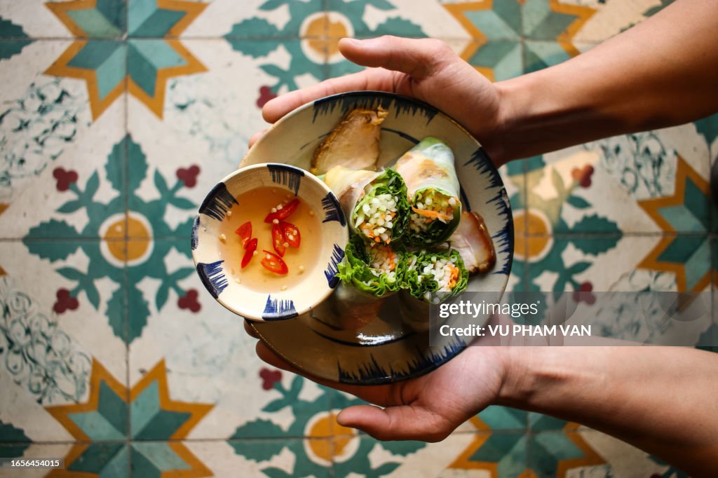Vietnamese leaf vegetable paper rolls with stewed belly pork on floral pattern background