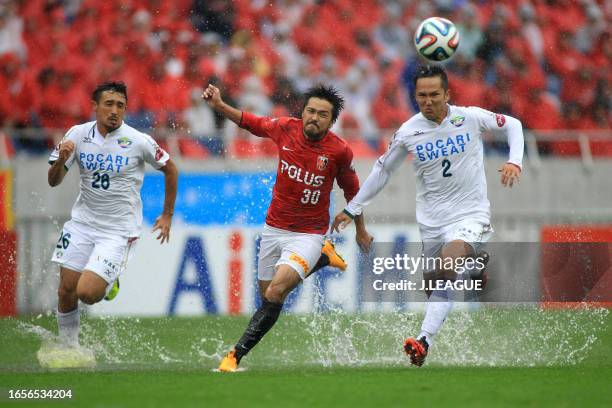 Shinzo Koroki of Urawa Red Diamonds competes for the ball against Yuya Hashiuchi and Yohei Fukumoto of Tokushima Vortis during the J.League J1 match...