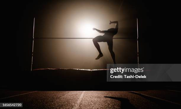 sportsman high jumping over horizontal bar. dark silhouette - horizontal bar stock pictures, royalty-free photos & images