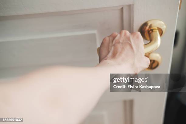 female hand opening the doorknob, close up - body men close up stock-fotos und bilder