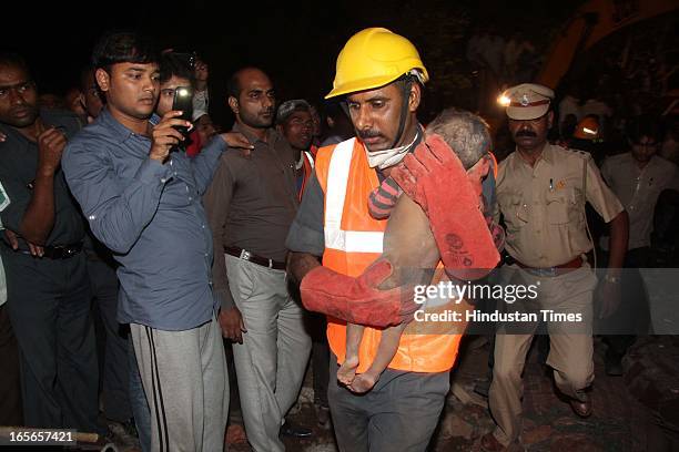 Rescue workers carry a infant child who survived the building collapse at Lucky compound on April 4, 2013 in Thane, India. The death toll has risen...