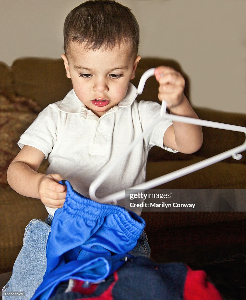 Boy putting pants on hanger