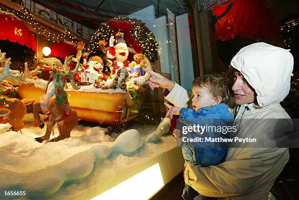 Child looks at a Christmas scene depicted in a Macy's at Herald Square department store window during the unveiling of the retailer's holiday windows...