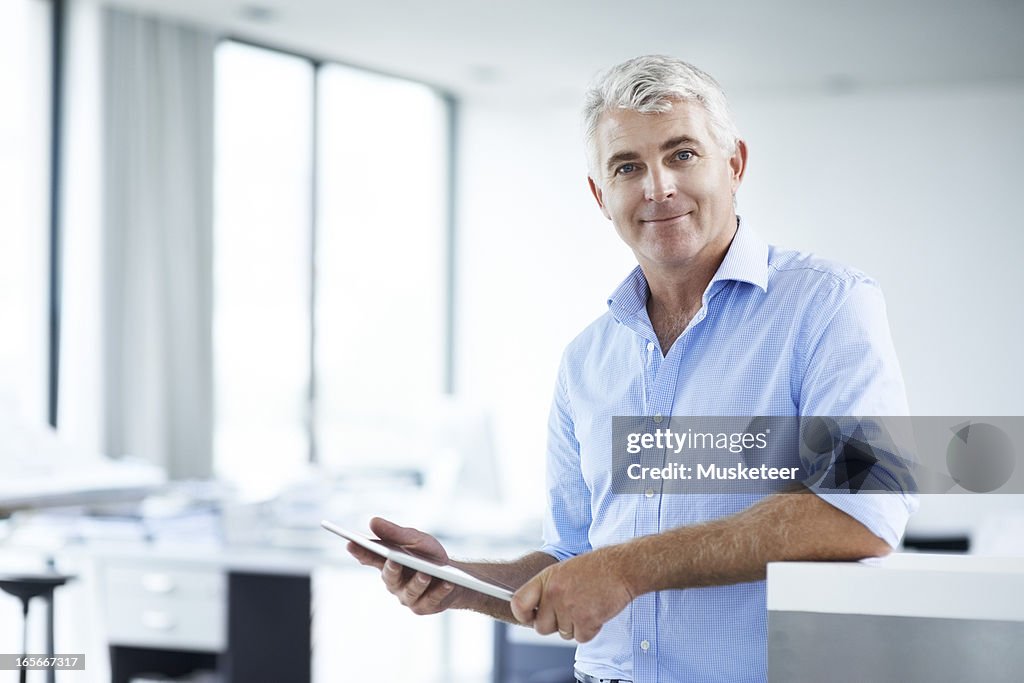 Man looking in camera while working on his tablet