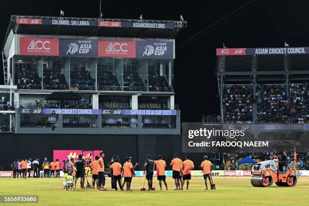 Ground staff remove water from the outfield after a rain delay during the Asia Cup 2023 super four one-day international cricket match between India...