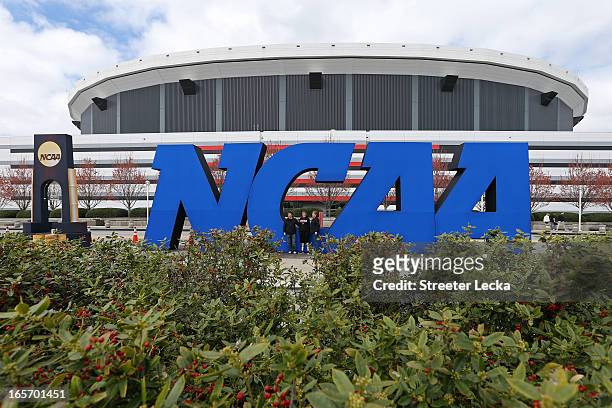 Fans stand next to a giant NCAA logo outside of the stadium on the practice day prior to the NCAA Men's Final Four at the Georgia Dome on April 5,...