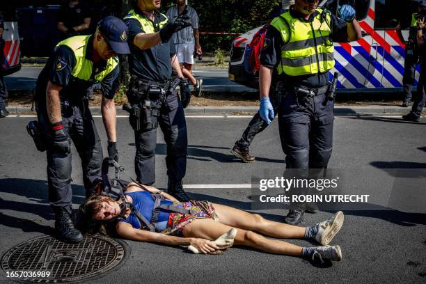 Police officers remove a climate activist from Extinction Rebellion group who is blocking the Utrechtsebaan highway during a demonstration against...