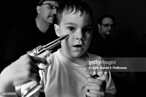 Nathan Jenkins son of Ku Klux Klan Imperial Wizard Bradley Jenkins, points a toy gun at himself in a hotel room with his father and members of Aryan...