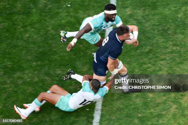 Scotland's number eight Jack Dempsey is tackled by South Africa's flanker and captain Siya Kolisi and South Africa's fly-half Manie Libbok during the...