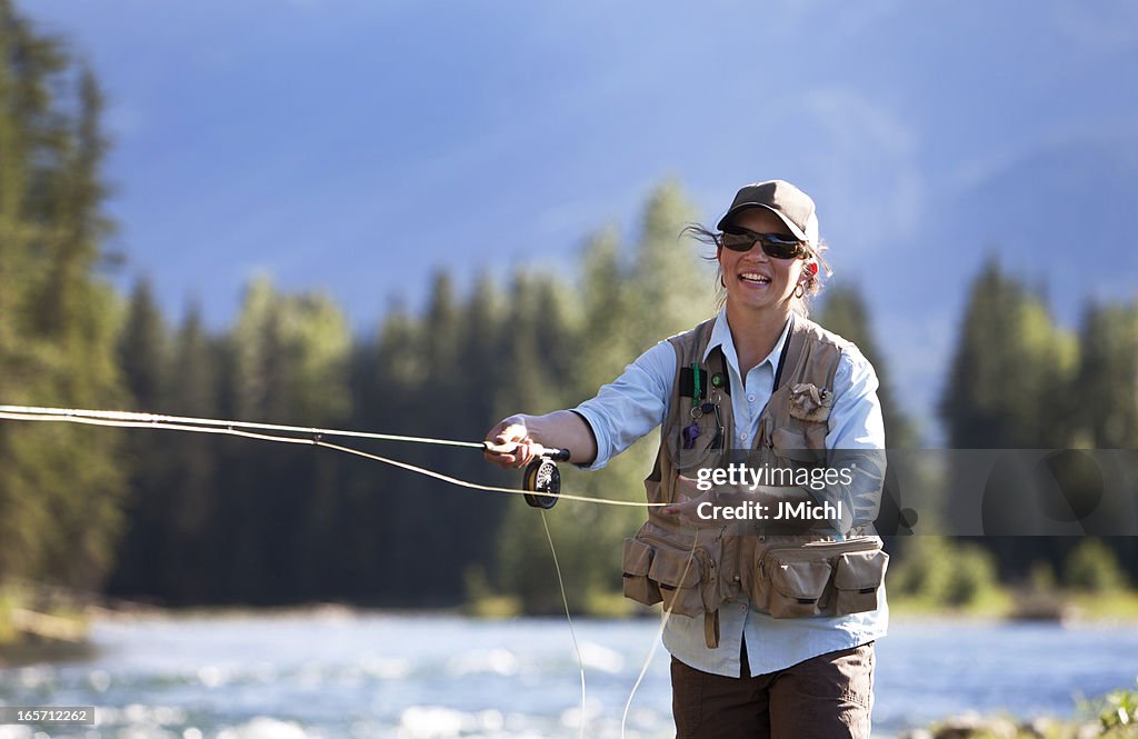 Frau Fliegenfischen von Regenbogenforelle auf einem British Columbia River.