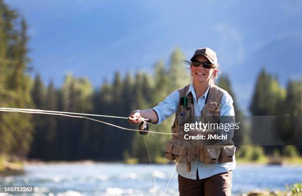 smiling woman fly-fishing trout on a british columbia river - fly fishing stock pictures, royalty-free photos & images