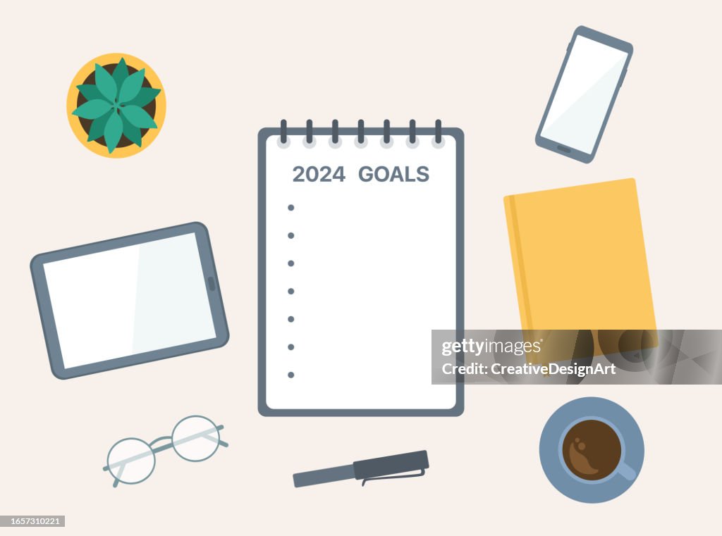 2024 New Year Goals. High Angle View Of Table Workspace With Notepad, Smartphone, Digital Tablet And Coffee Cup