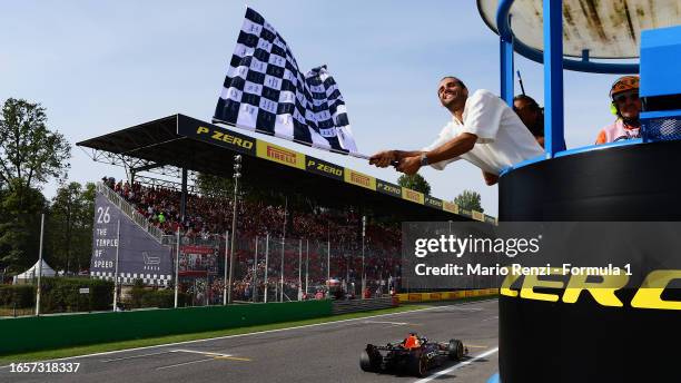 Race winner Max Verstappen of the Netherlands and Oracle Red Bull Racing takes the chequered flag waved by Gianmarco Tamberi during the F1 Grand Prix...