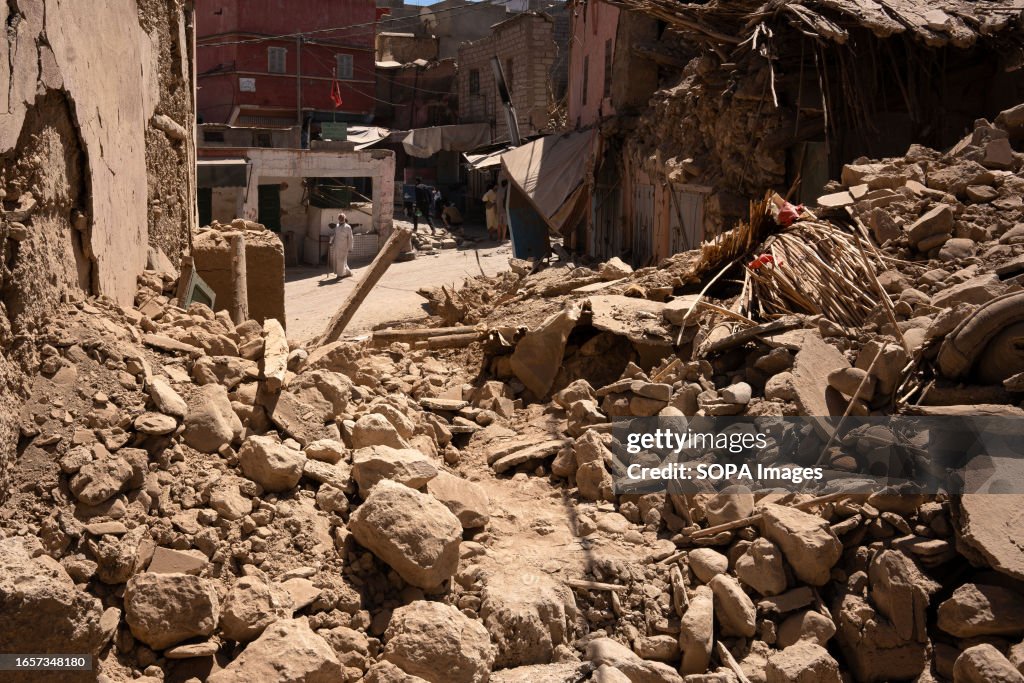 A man walks through the wreckage of several houses...