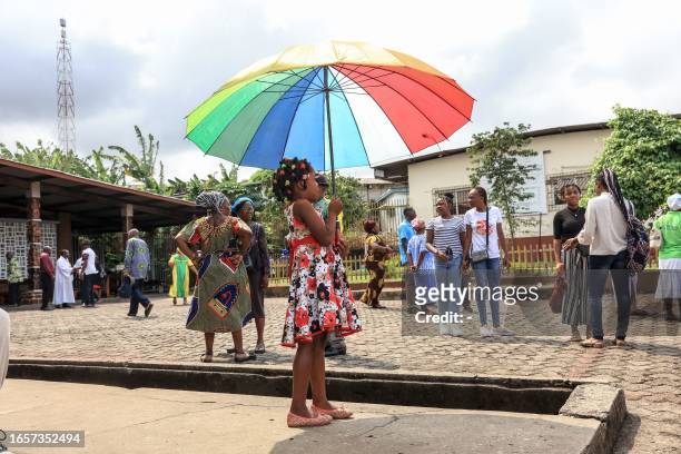 Young girl holds an umbrella in front of Saint-Michel de Nkembo church, in Libreville on September 10, 2023.