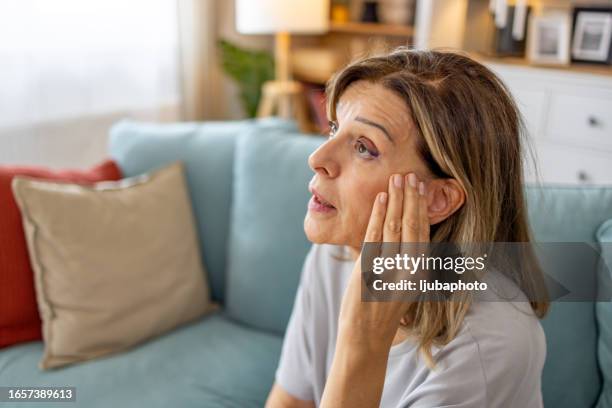 senior woman at home touching ear with hand with painful expression because of earache. - ear stockfoto's en -beelden