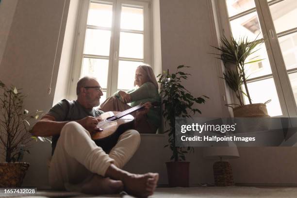 senior man playing a romantic song on acoustic guitar for his wife. - een serenaden brengen stockfoto's en -beelden