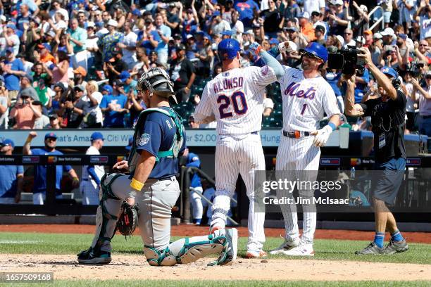 Cal Raleigh of the Seattle Mariners looks on as Pete Alonso of the New York Mets celebrates his third inning two-run home run with teammate Jeff...