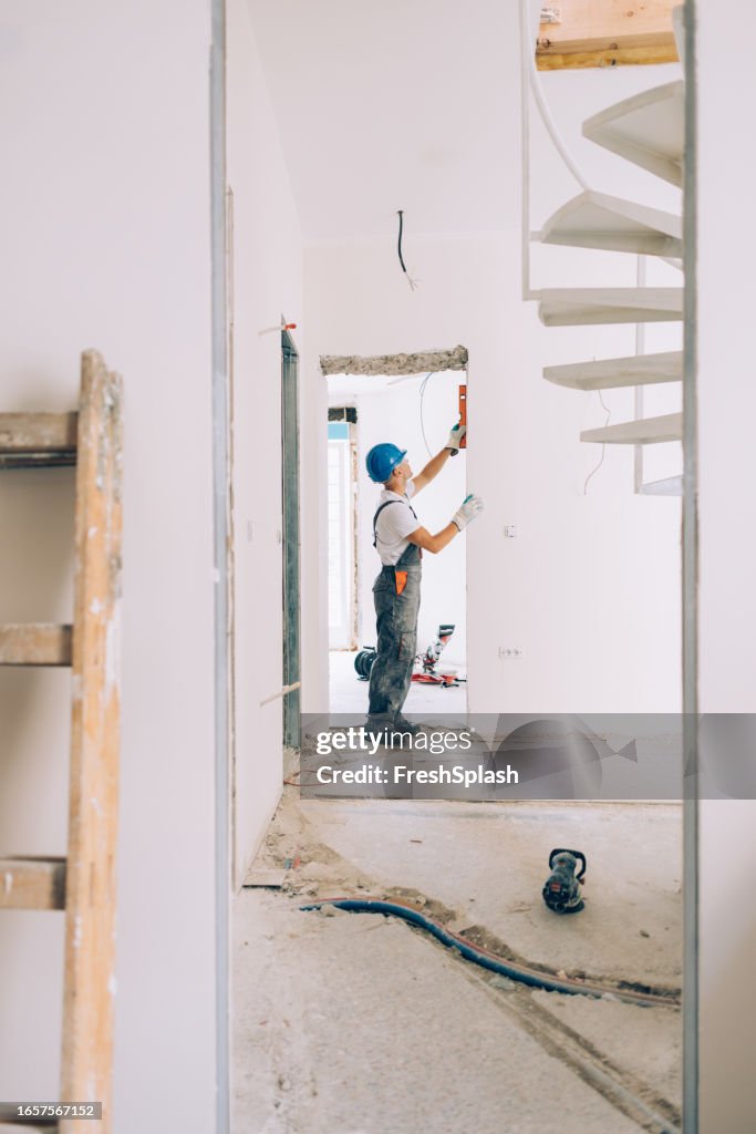 Caucasian Construction Worker Checking the Level Measurements inside an Apartment
