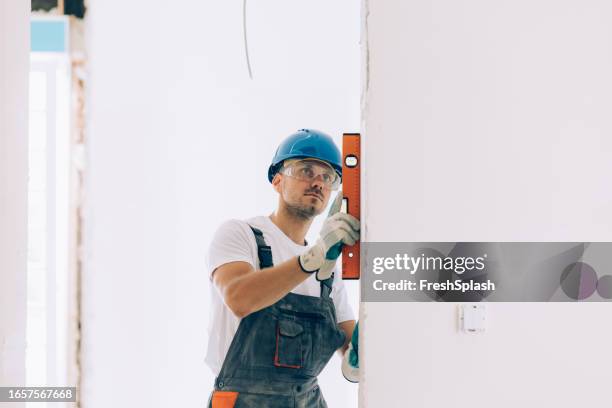 caucasian construction worker checking the level measurements inside an apartment - waterpas stockfoto's en -beelden