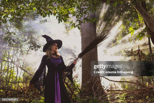 portrait witch holds the magic broom in the rustic  forest on halloween day - witch flying on broom stock pictures, royalty-free photos & images