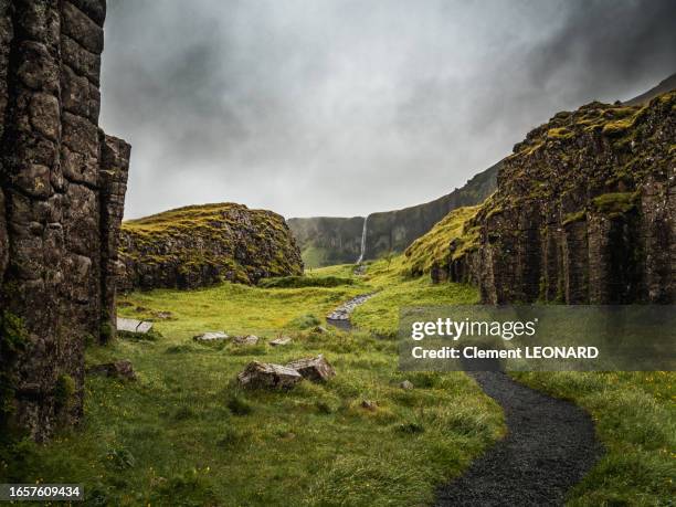 distant view of the waterfall foss á síðu (foss a sidu) in the middle of the basalt columns of the dverghamrar cliffs, kirkjubaejarklaustur (kirkjubæjarklaustur), south iceland (sudurland, suðurland). - fossa river stock pictures, royalty-free photos & images