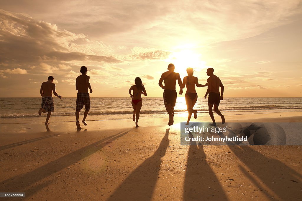 Menschen am Strand Laufen auf dem Wasser bei Sonnenuntergang