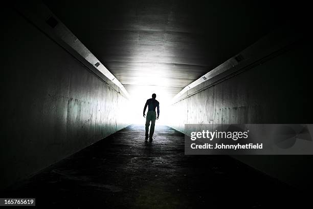 lone man walking through tunnel - corridor light at end stock pictures, royalty-free photos & images