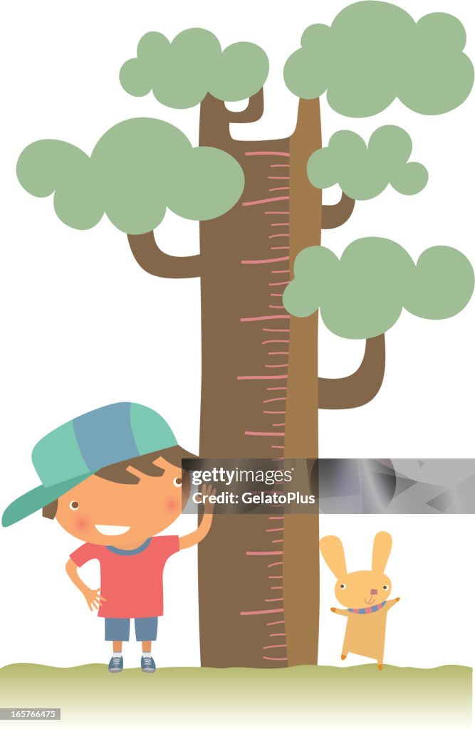 Young boy and pet checking their height against a tree