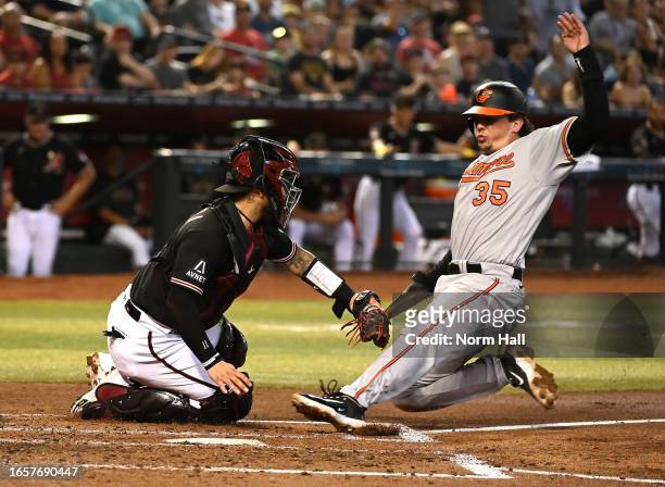 Adley Rutschman of the Baltimore Orioles is tagged out at home by Jose Herrera of the Arizona Diamondbacks during the second inning at Chase Field on...