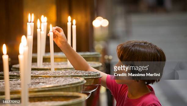 little girl lighting a candle in church - religious mass 個照片及圖片檔