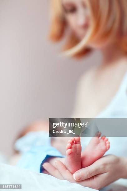 woman breastfeeding newborn and gently holding the baby's feet - feet sucking stock pictures, royalty-free photos & images